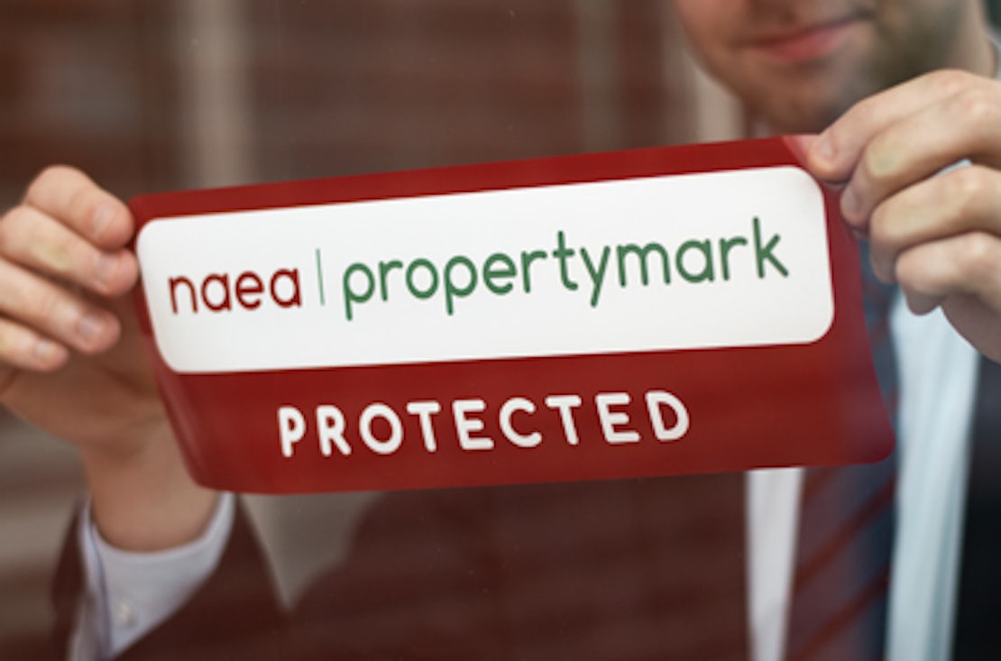 man sticking a NAEA Propertymark sticker on a window