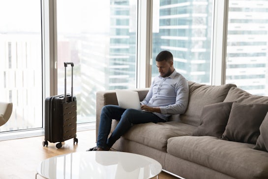 Focused young professional man working on laptop on business trip
