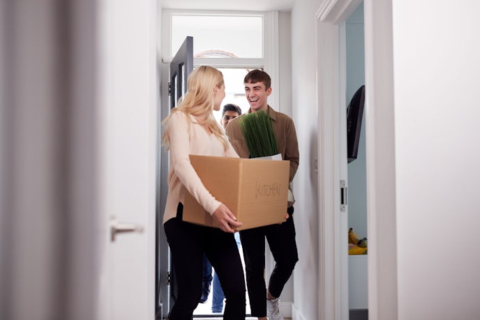 Group Of College Student Carrying Boxes Moving Into Accommodation Together