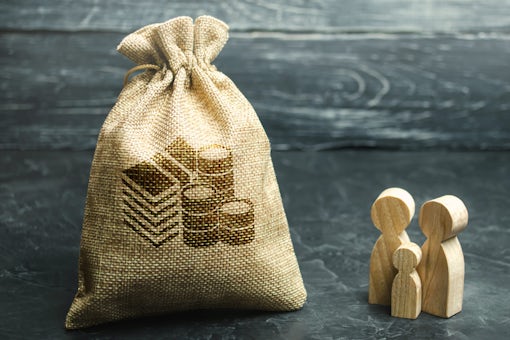 Miniature wooden family figurines stand near a money bag.