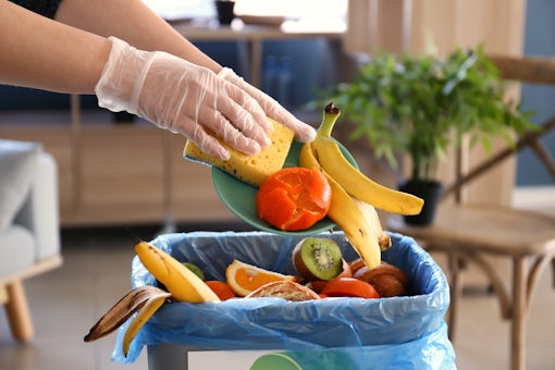 person throwing away food waste into a bin