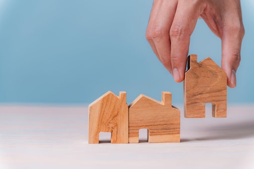 hand selecting a wooden house model