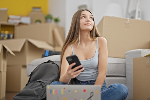 teenage girl on her phone amongst moving boxes