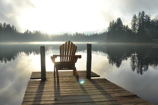 deck chair on dock overlooking a peaceful lake