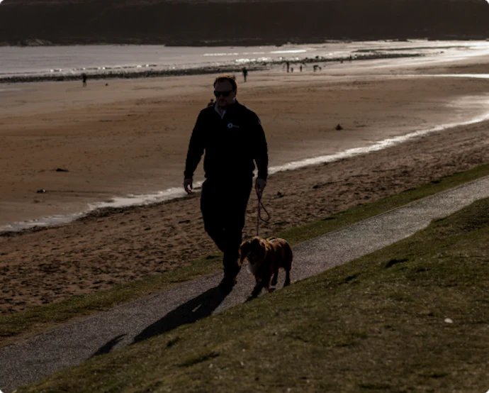 jordan, founder of st andrews property co and head property agent walking his dog on the beach