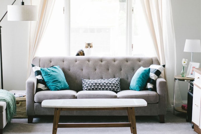 living room essentials in a holiday home including a grey sofa with blue pillows