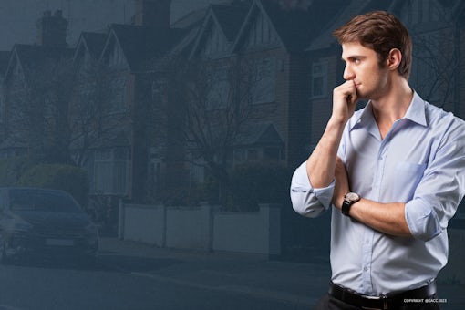 Thoughtful man in front of a street with residential properties.