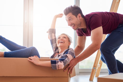 Man pushing woman in a box, while moving together.
