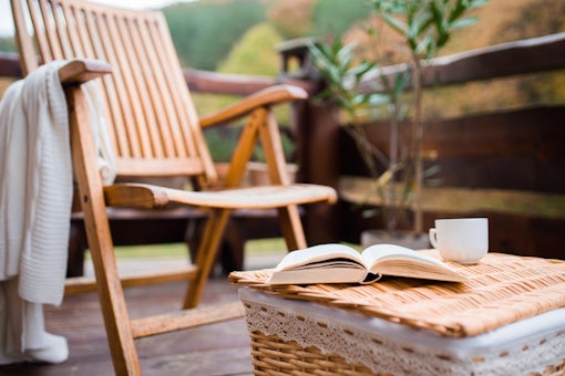 A wooden chair and a book on a basket on a terrace on a sunny day in autumn.