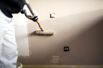 Handy man decorating walls with paint. Construction plaster worker painting and renovating with professional tools