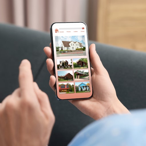 Woman choosing dwelling on house hunting website via smartphone indoors, closeup