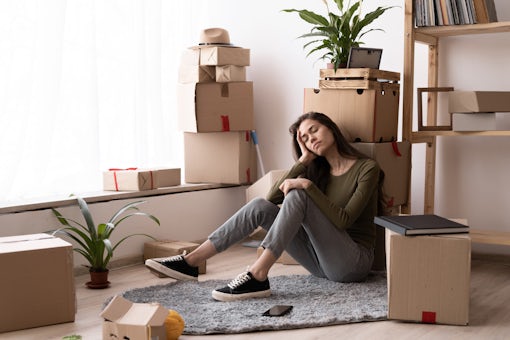 Young tired girl feeling fatigue on hard moving out day, sleeping woman with heap of moving boxes sitting on in floor house