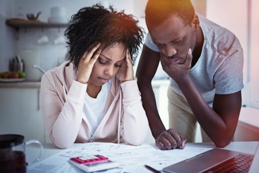 Young stressed african american couple in trouble, have no money to pay debts, to pay rent for appartment. Wife holding head in despair, can not pay bills, having financial troubles. Household budget