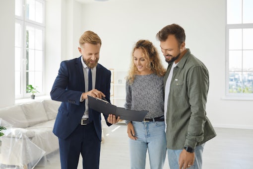 Couple who are buying a new house meet with their real estate agent and sign a contract