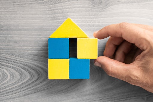 hand building home with wooden blocks, Ukraine flag colors