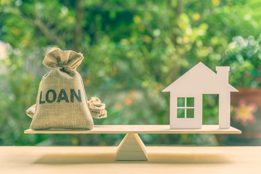 Home loan, reverse mortgage and saving for a real estate concept : House model, loan bag on basic balance scale, depicts saving for a house or flat manageable and turn a home buying dream into reality
