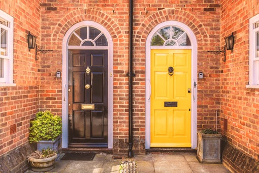 Two residential front doors, one black one yellow and a red bric