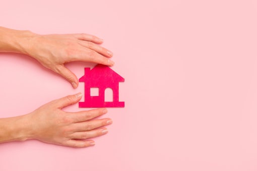 Hand Holding Pink house on pink background. New home concept