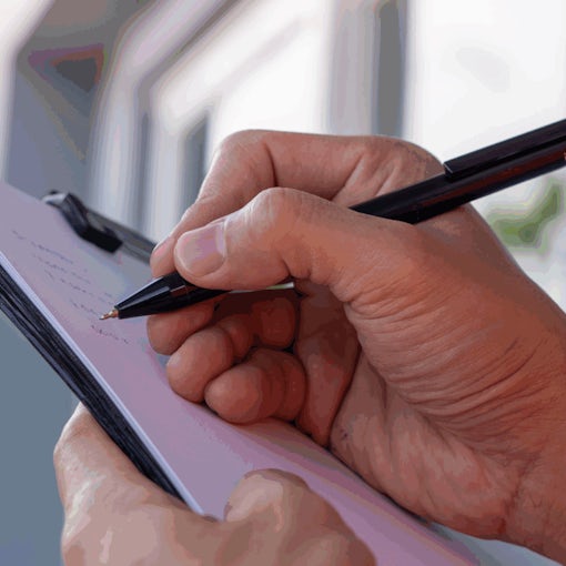 Close-up of a landlord’s hand writing on a property inventory checklist clipboard