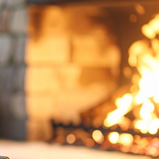 Cozy living room with a warm fireplace and blanket, symbolising winter preparation for UK landlords and rental property maintenance checklist by Belvoir.