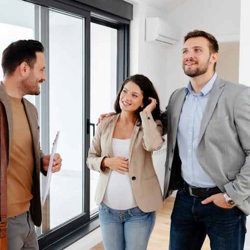 Estate agent giving a property tour to two potential buyers inside a bright modern home.