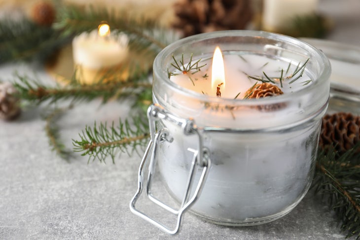 Burning scented conifer candle and Christmas decor on grey table
