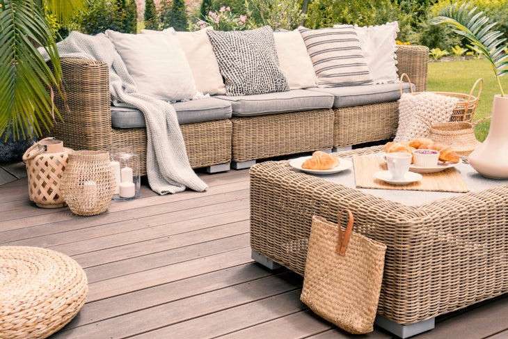 Wicker patio set with beige cushions standing on a wooden board