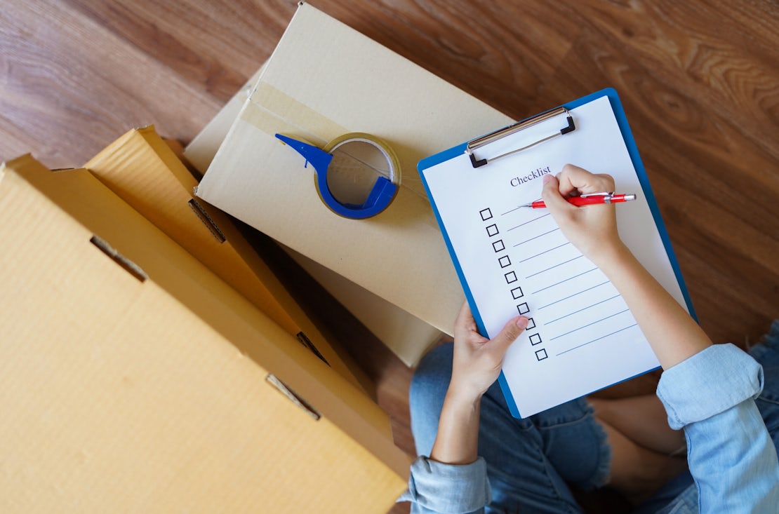 Top view of woman checking package with checklist at home