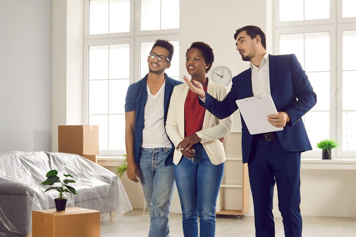 Caucasian male realtor presenting young African American buyers new big and bright apartment.