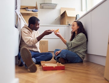Young Couple Celebrate Moving Into New Home Sitting On Floor Eat