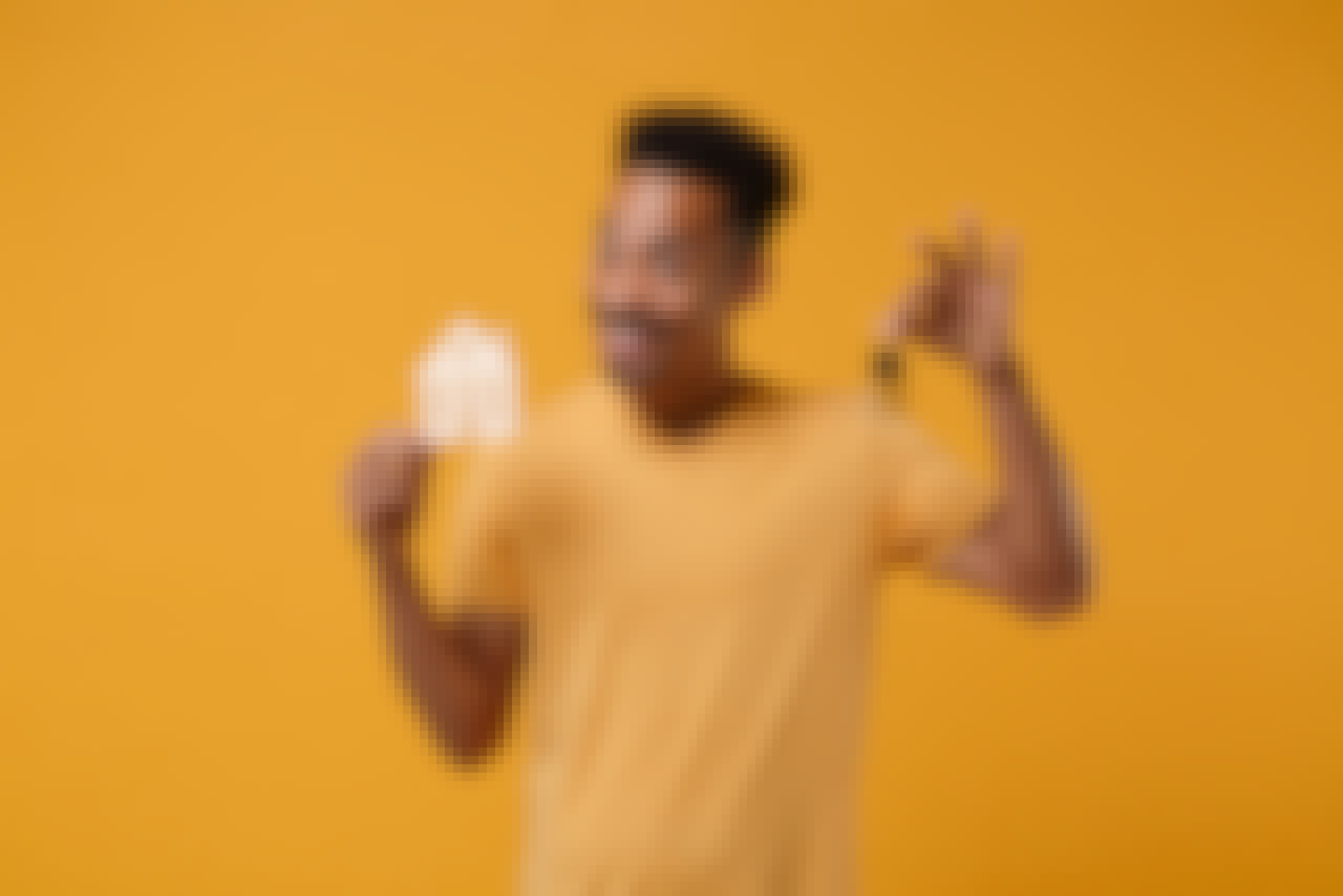 Smiling young african american guy in casual t-shirt posing isolated on yellow orange background, studio portrait. People lifestyle concept. Mock up copy space. Hold in hands house and bunch of keys.