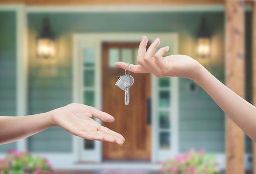 Mani con chiavi con sfondo porta di casa
