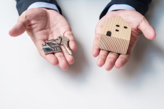 Letting Agent Hands Holding a Key and Wooden Home Model