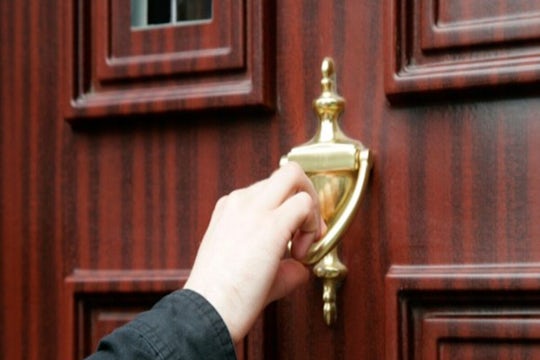 Mans hand using door knocker on a door
