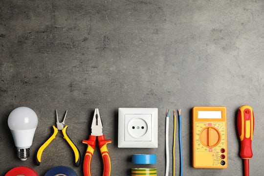 Electrician’s tools and space for text on gray background, flat lay