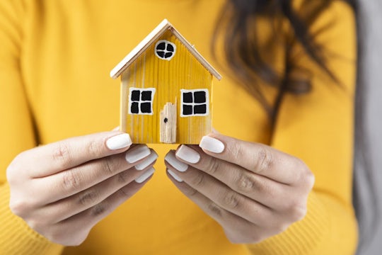 Woman holding little yellow house.