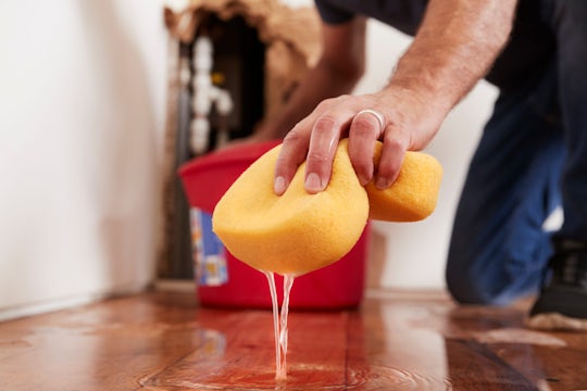 Man mopping up water from the floor with a sponge.