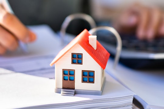 House model on top of a folder with transaction documents.
