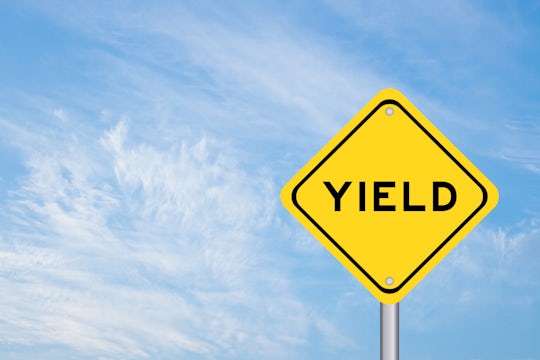 Yellow transportation sign with word yield on blue color sky background