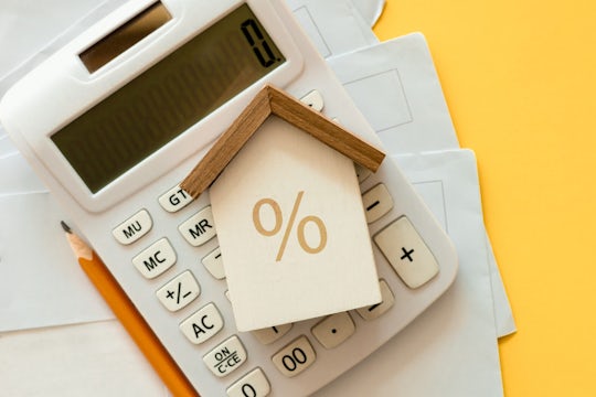 close up top view on home model with calculator and invoice mail on yellow color background with space for money management ,home loan and personal financial concept