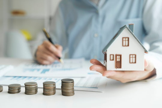 Stack coins with model house for investment loans